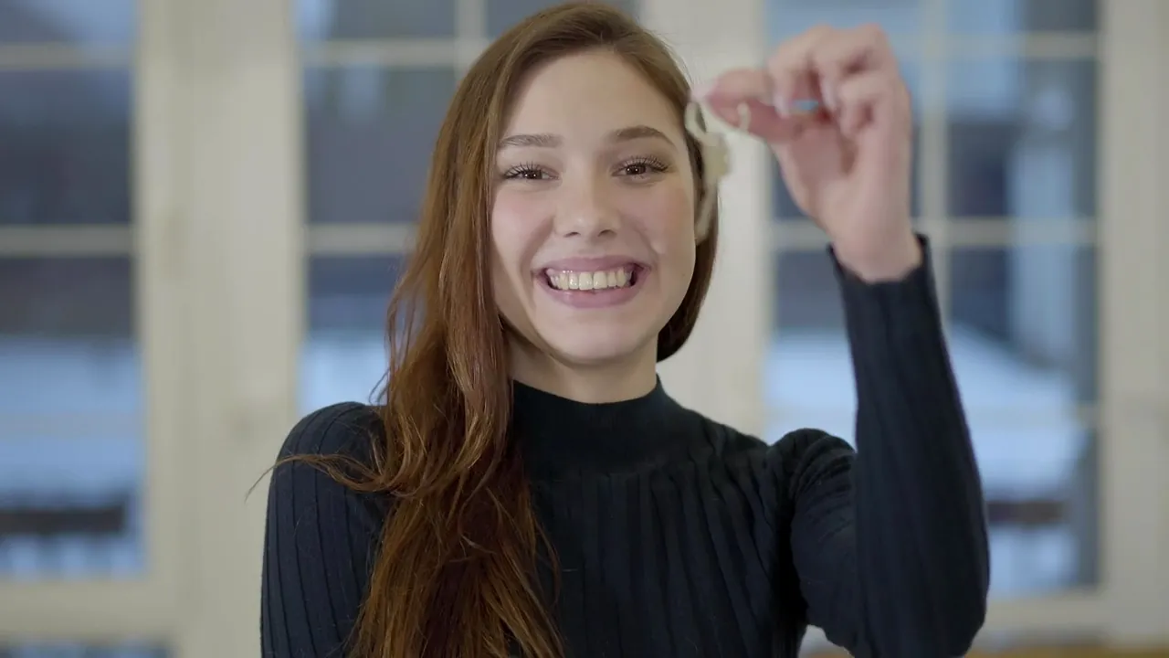 Mulher sorrindo com a chave da casa nova na mão