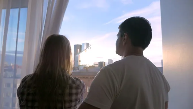 Casal olhando a cidade pela janela do apartamento novo