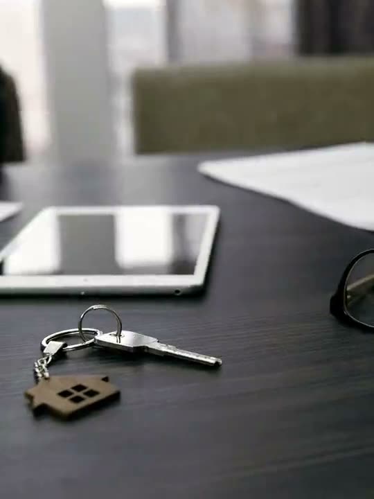 Chaves de casa sobre a mesa ao lado de um tablet e documentos